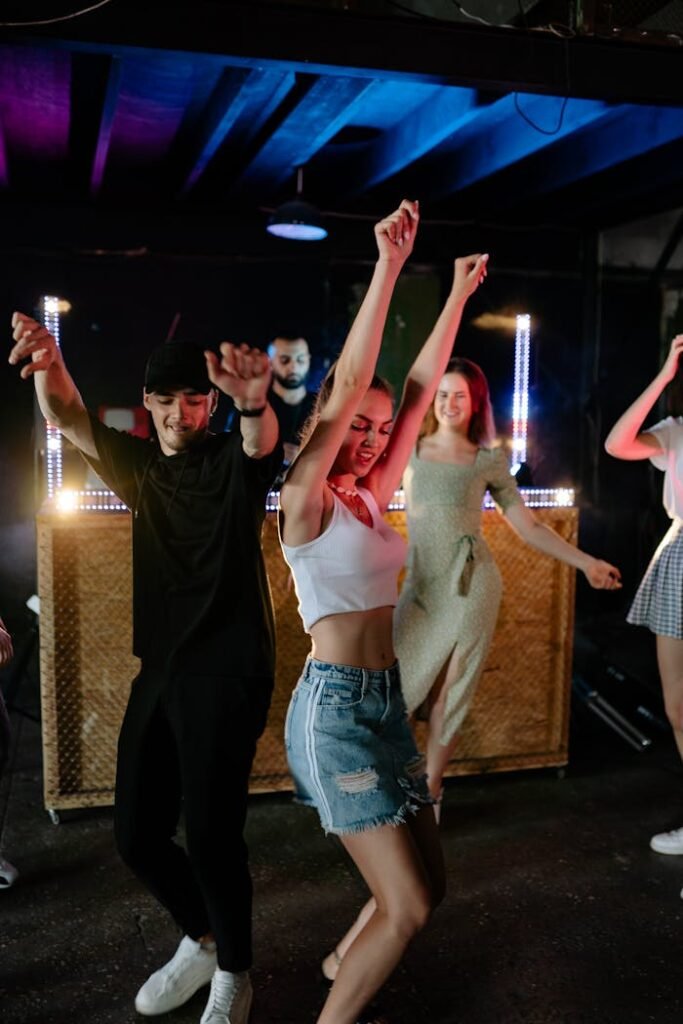 Galería Group of adults dancing energetically at a nightclub with vibrant lighting and a lively atmosphere.